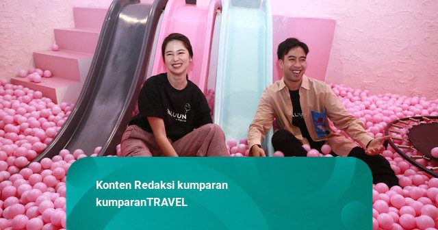 Two visitors sitting in a pink ball pit beside pastel slides at Baluun by HALUU