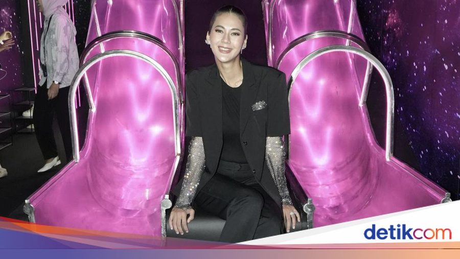A visitor seated between pink sculpted chairs inside the DREAMscape installation