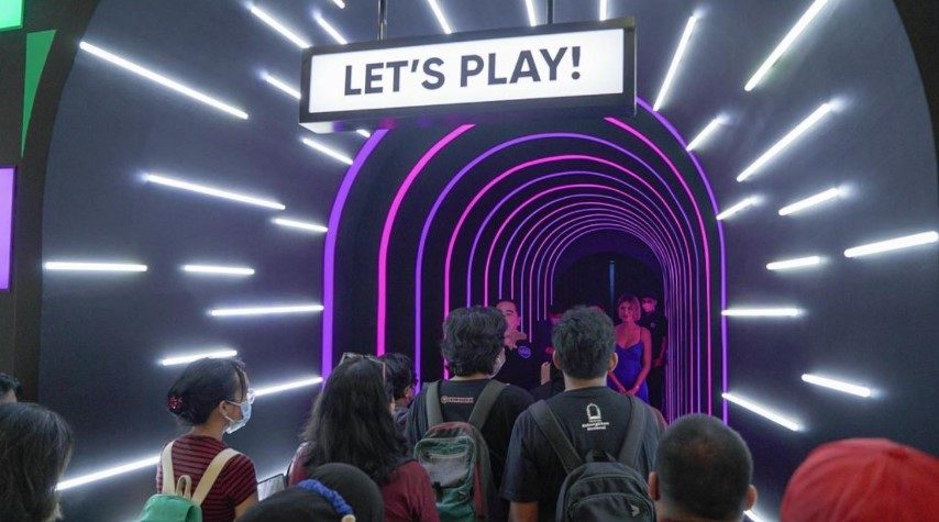 Visitors queuing at a neon tunnel entrance under a LET'S PLAY sign at Hotel for Play