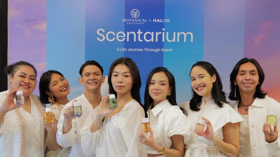 Eight people in white holding perfume bottles in front of the Scentarium launch backdrop